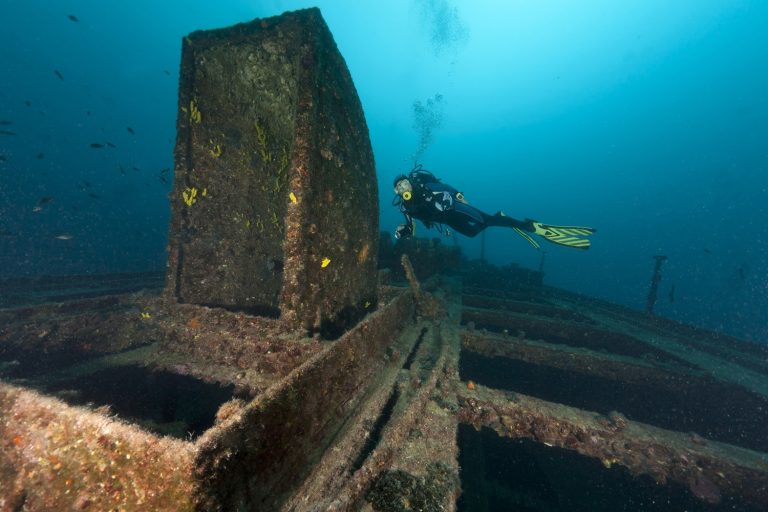 Plongeur explorant une épave rouillée en Bretagne, France.
