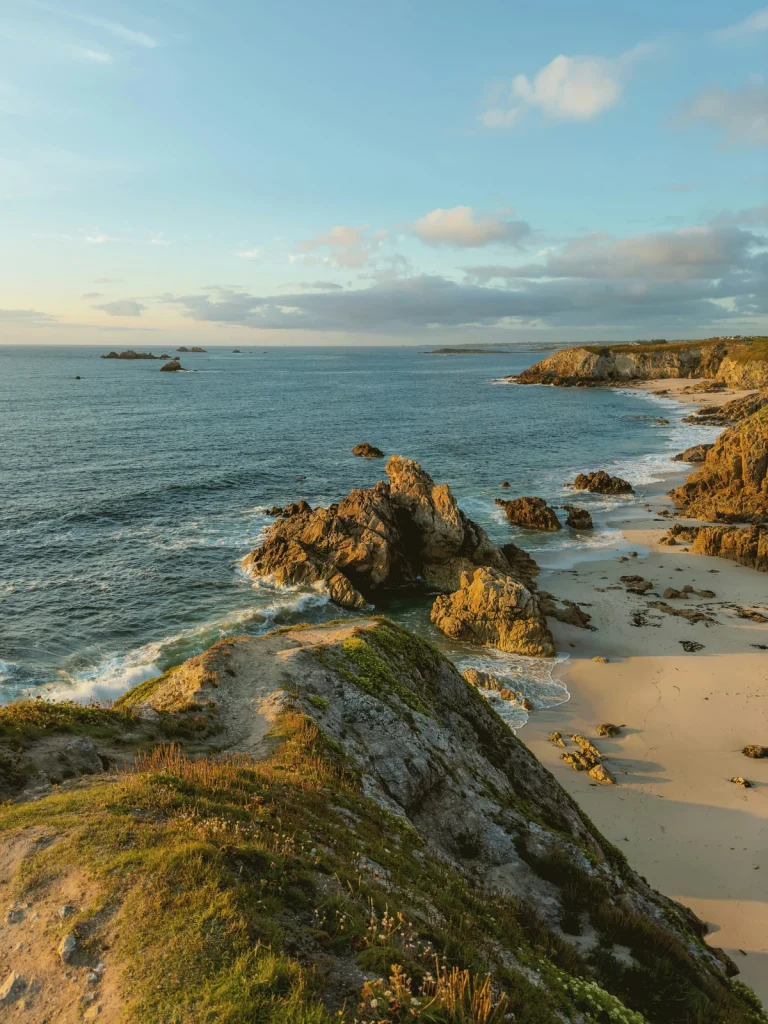 Paysage côtier breton au coucher du soleil, falaises rocheuses et mer calme